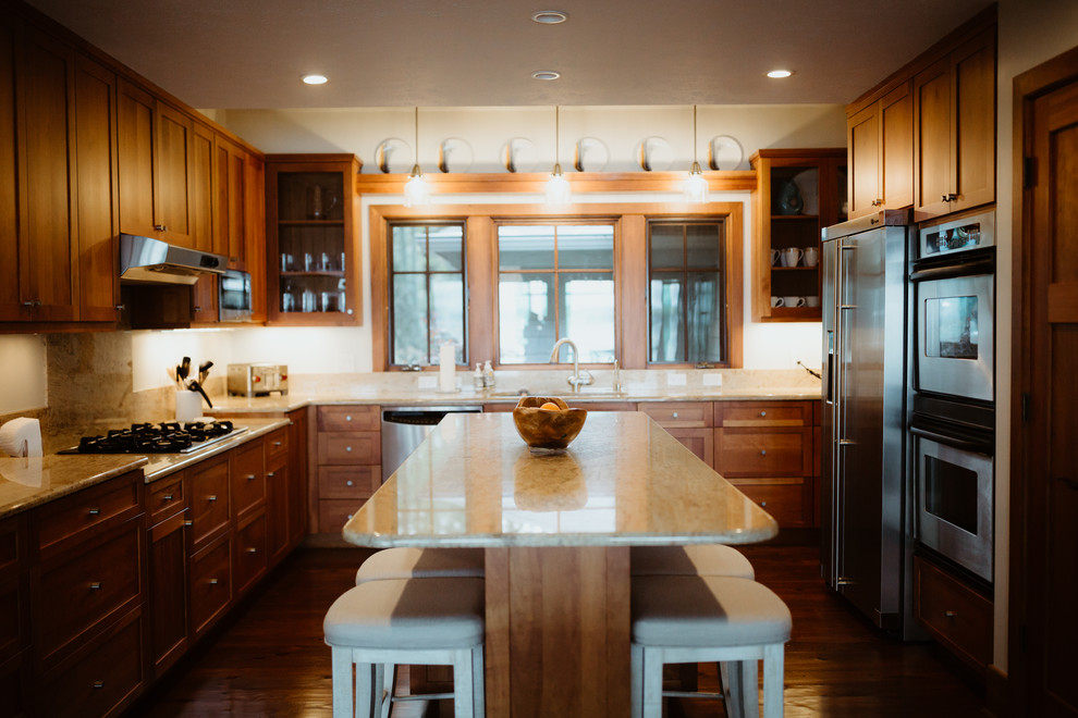 Example of a large minimalist enclosed kitchen design with dark wood cabinets, beige backsplash, stainless steel appliances, an island and beige countertops