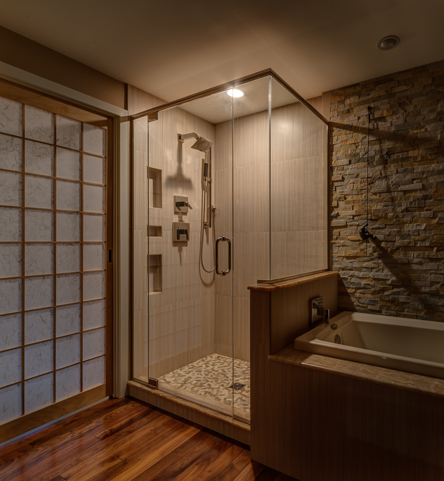 Inspiration for a mid-sized asian master bathroom in Boston with furniture-like cabinets, light wood cabinets, a drop-in tub, a corner shower, beige tile, pebble tile, dark hardwood floors and an undermount sink.