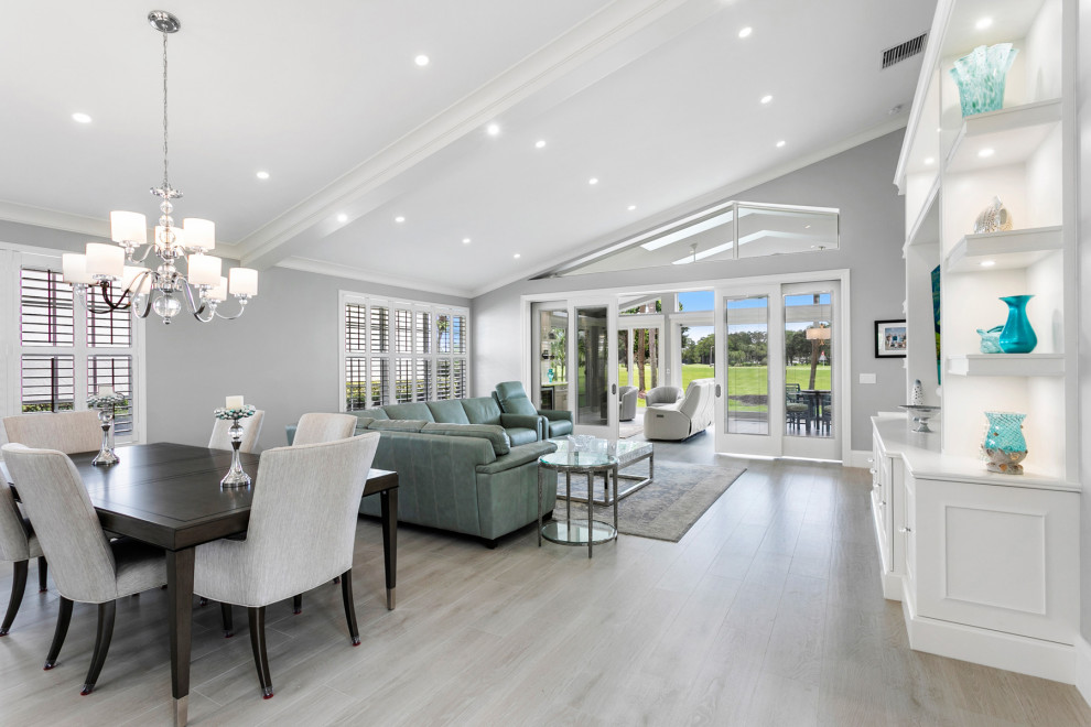 This is an example of an expansive transitional open concept living room in Miami with grey walls, porcelain floors, a built-in media wall, grey floor and vaulted.