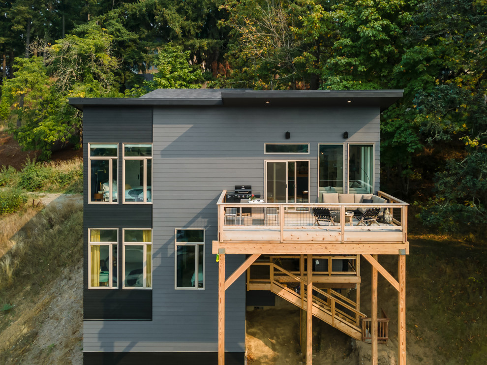 Imagen de fachada de casa gris y negra minimalista grande de dos plantas con revestimientos combinados, techo de mariposa, tejado de teja de madera y tablilla