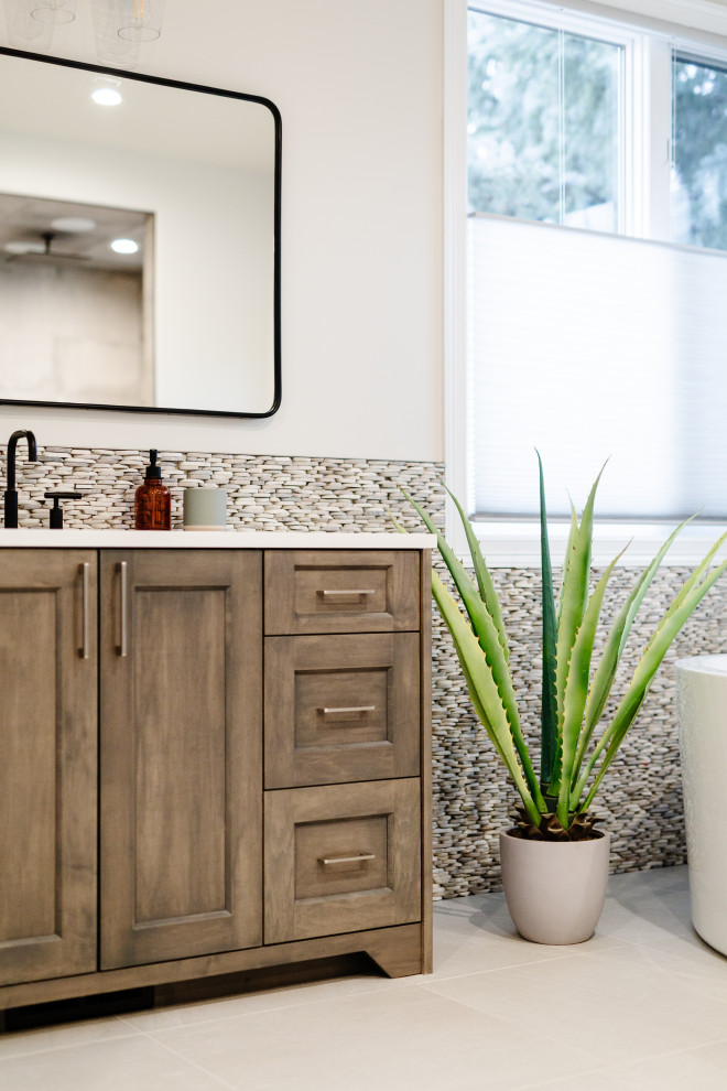 Large beach style master bathroom in Denver with recessed-panel cabinets, medium wood cabinets, a freestanding tub, an alcove shower, gray tile, pebble tile, cement tiles, quartzite benchtops, beige floor, an open shower, white benchtops, a double vanity and a freestanding vanity.