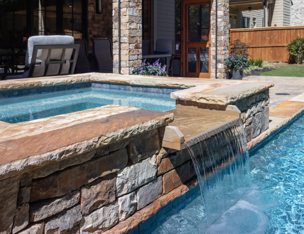 This is an example of a mid-sized contemporary backyard rectangular natural pool in Atlanta with a hot tub and natural stone pavers.