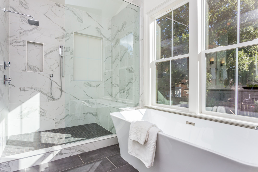 Photo of a large transitional master bathroom in Raleigh with raised-panel cabinets, white cabinets, a freestanding tub, an alcove shower, a two-piece toilet, gray tile, ceramic tile, white walls, ceramic floors, an undermount sink, marble benchtops, grey floor and a hinged shower door.