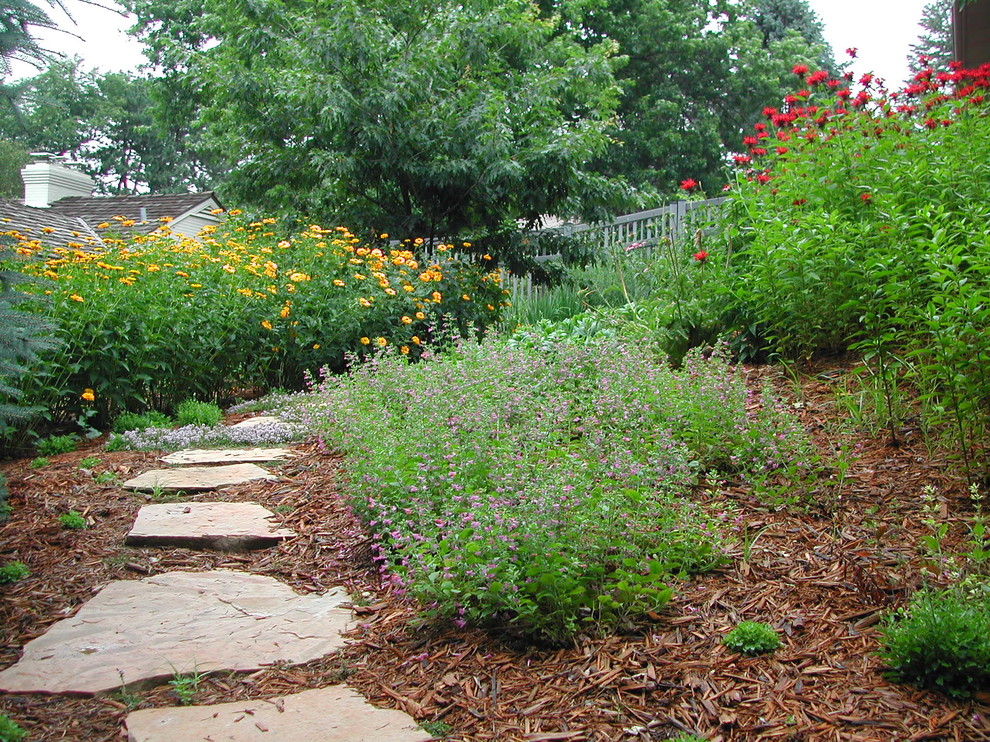 Inspiration for a large traditional sloped full sun formal garden in Omaha with natural stone pavers and a garden path.