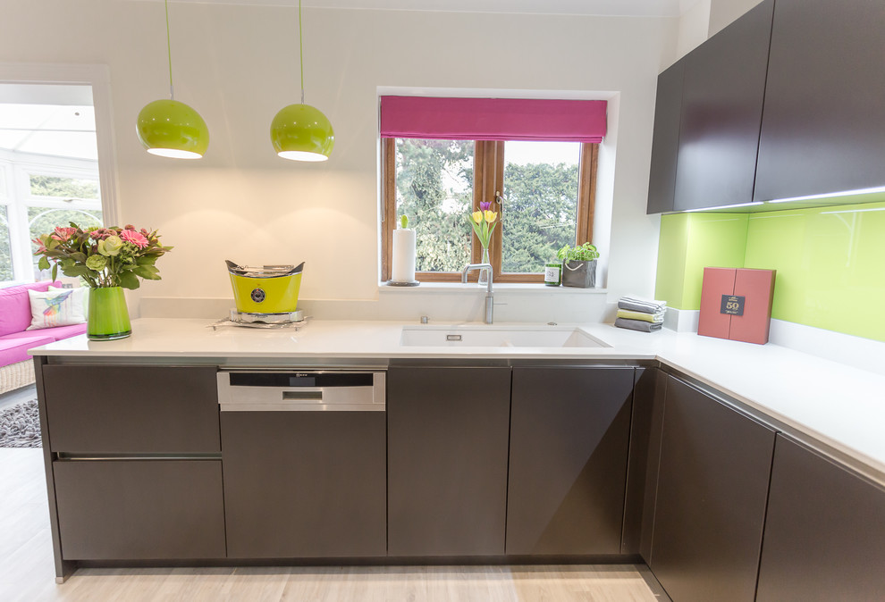 Design ideas for a mid-sized modern galley eat-in kitchen in Hertfordshire with a double-bowl sink, flat-panel cabinets, grey cabinets, quartzite benchtops, green splashback, glass sheet splashback, black appliances, no island and white benchtop.