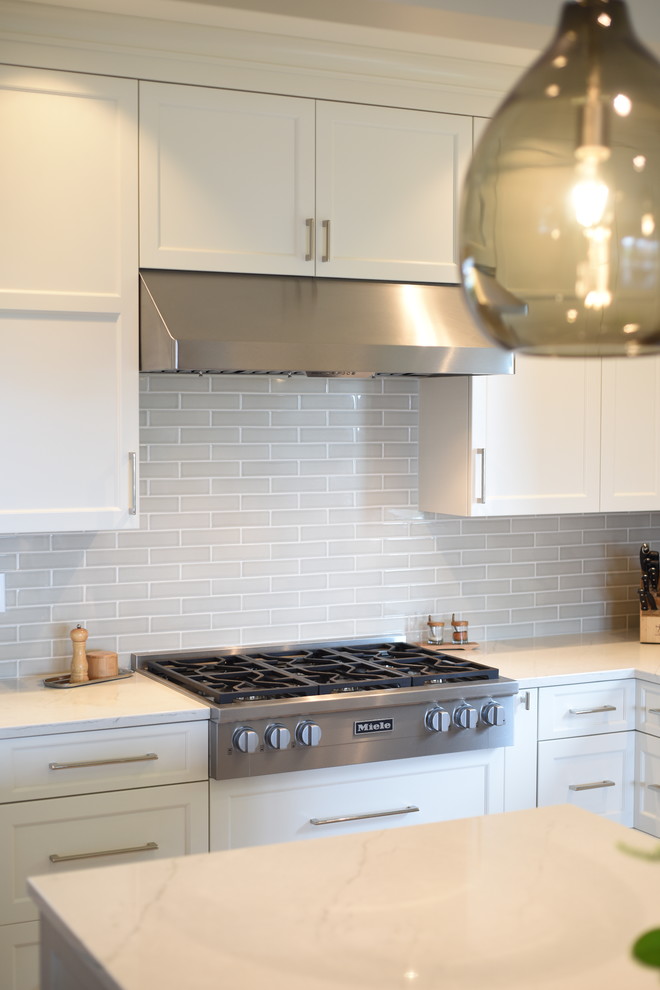 Example of a transitional ceramic tile kitchen design in Seattle with shaker cabinets, white cabinets, quartzite countertops, subway tile backsplash, stainless steel appliances, an island and white countertops