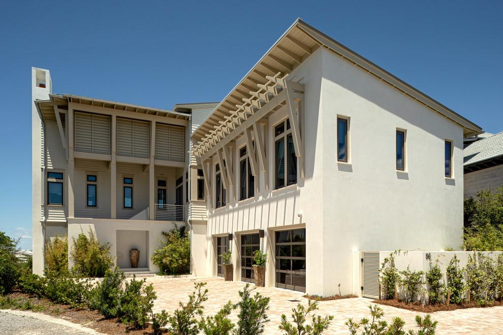 Foto della facciata di una casa ampia beige stile marinaro a tre piani con rivestimenti misti, copertura in metallo o lamiera, tetto grigio e pannelli sovrapposti