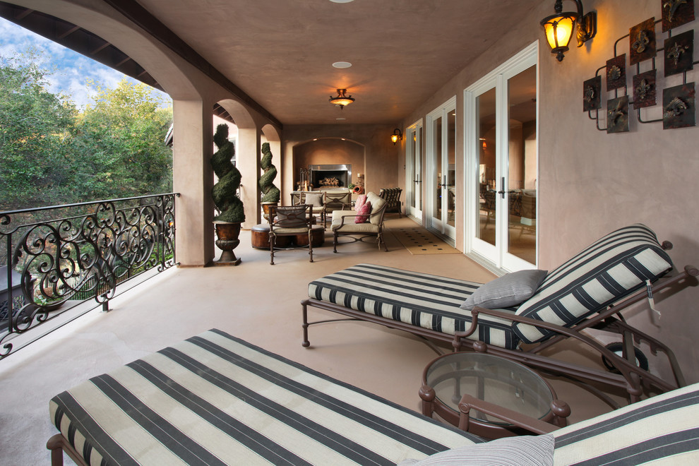 Photo of a mediterranean deck in Orange County with a fire feature and a roof extension.