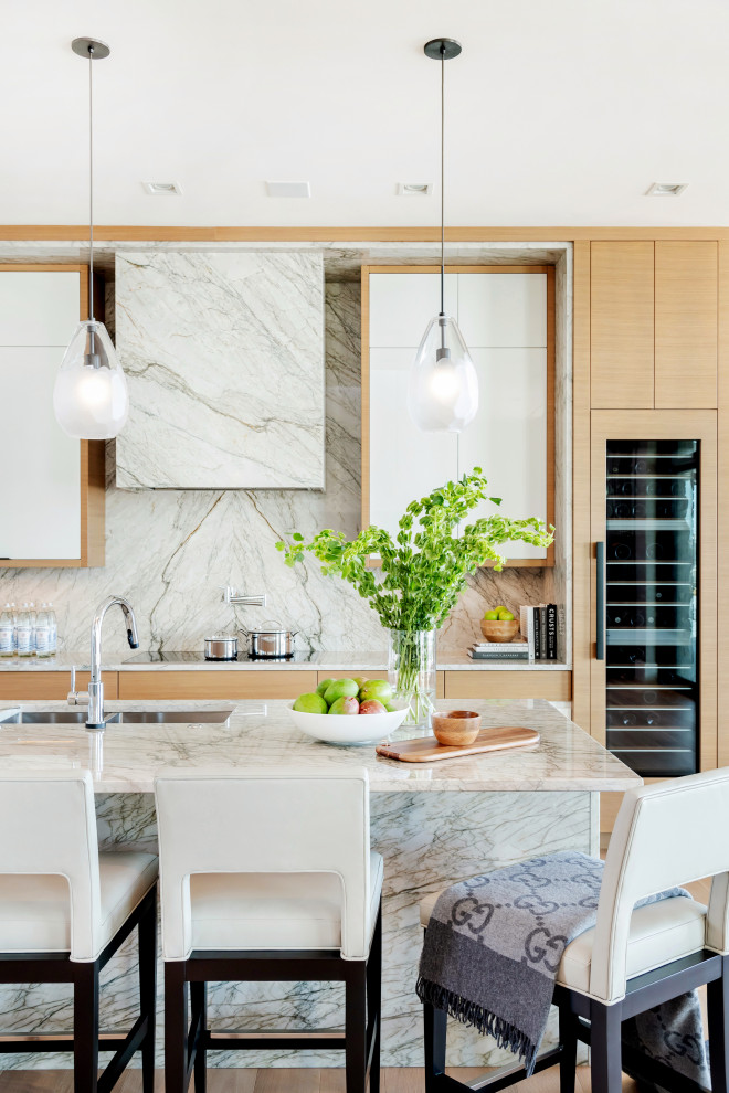 Photo of a large contemporary l-shaped kitchen pantry in Other with an undermount sink, flat-panel cabinets, light wood cabinets, marble benchtops, white splashback, stone slab splashback, panelled appliances, light hardwood floors, with island, beige floor and white benchtop.