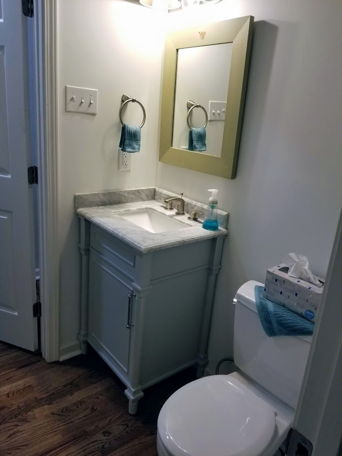 Small transitional powder room in Atlanta with beaded inset cabinets, grey cabinets, white walls, medium hardwood floors, an undermount sink, marble benchtops, brown floor and grey benchtops.