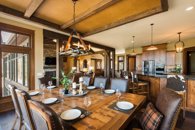 Photo of an expansive country kitchen/dining combo in New York with brown walls, dark hardwood floors, a stone fireplace surround, brown floor and no fireplace.