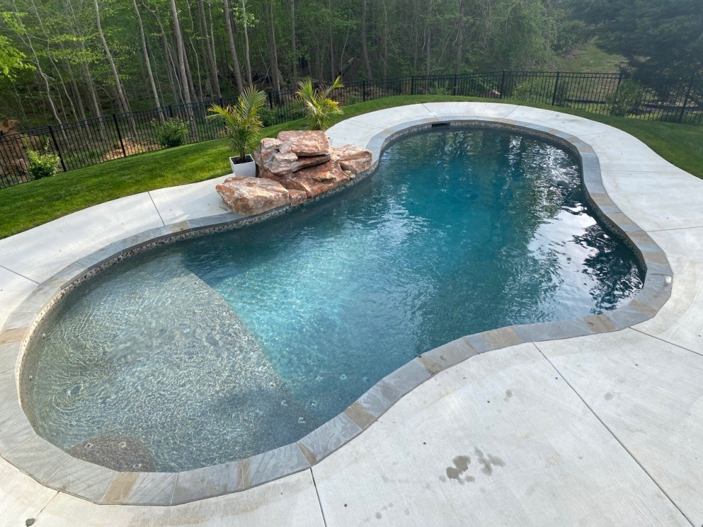 Inredning av en klassisk mellanstor anpassad pool på baksidan av huset, med betongplatta
