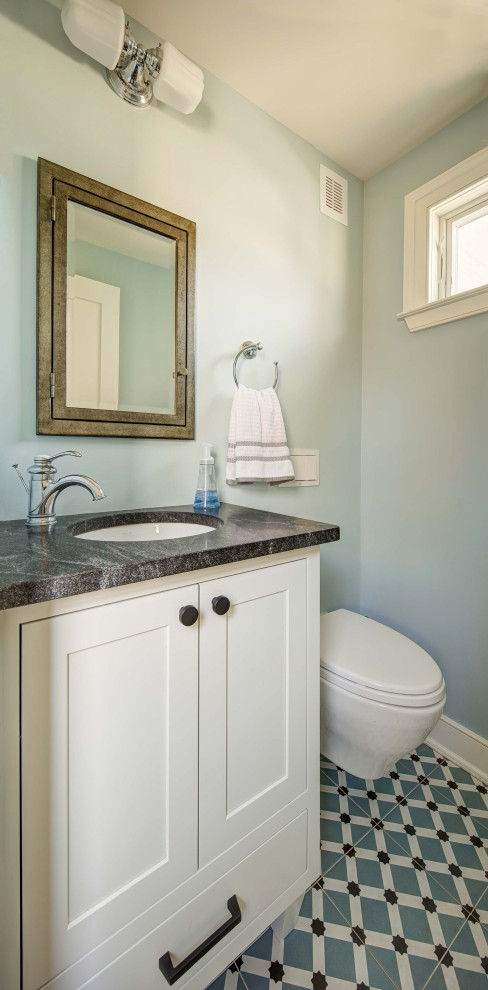 Photo of a small transitional powder room in New York with shaker cabinets, white cabinets, a wall-mount toilet, blue walls, porcelain floors, an undermount sink, granite benchtops, multi-coloured floor, grey benchtops and a built-in vanity.