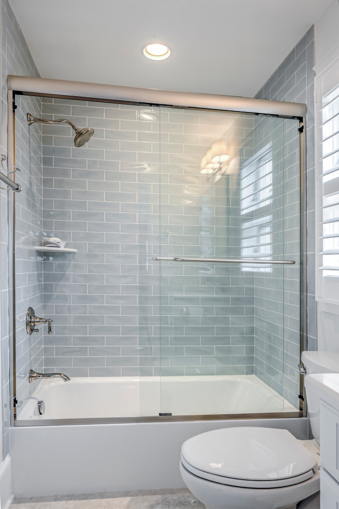 Photo of a small beach style 3/4 bathroom in Other with recessed-panel cabinets, white cabinets, an alcove tub, a shower/bathtub combo, a two-piece toilet, gray tile, subway tile, white walls, an undermount sink, granite benchtops, a sliding shower screen and white benchtops.