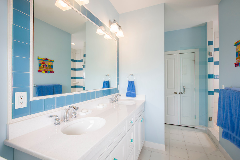 This is an example of a mid-sized beach style 3/4 bathroom in Baltimore with shaker cabinets, white cabinets, an alcove shower, blue tile, glass tile, blue walls, ceramic floors, an undermount sink, solid surface benchtops, white floor and a hinged shower door.