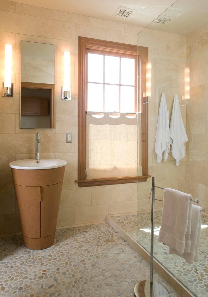 Inspiration for a large modern 3/4 bathroom in Portland Maine with a pedestal sink, furniture-like cabinets, an open shower, beige tile, ceramic tile, beige walls, pebble tile floors, light wood cabinets and solid surface benchtops.