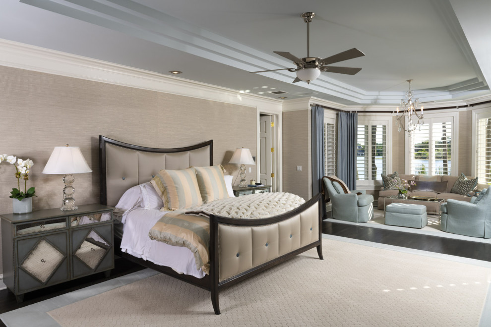 Design ideas for a large transitional master bedroom in Tampa with beige walls, dark hardwood floors, a standard fireplace, a stone fireplace surround, brown floor, recessed and wallpaper.