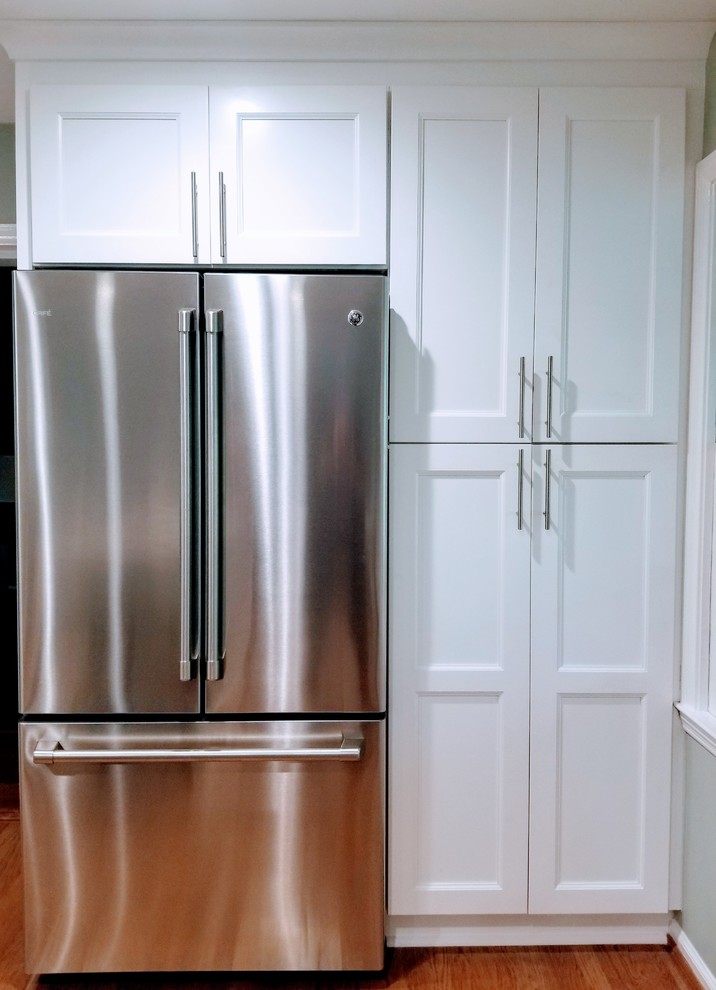 Inspiration for a large transitional u-shaped medium tone wood floor and brown floor enclosed kitchen remodel in Miami with an undermount sink, shaker cabinets, white cabinets, quartz countertops, white backsplash, subway tile backsplash, stainless steel appliances, an island and white countertops