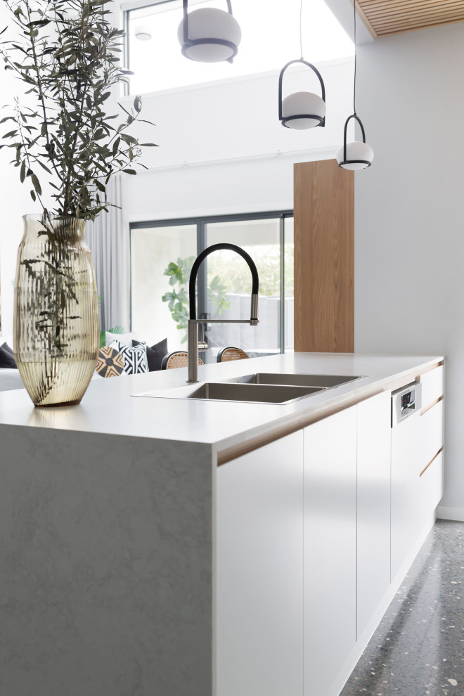 Modern kitchen in Canberra - Queanbeyan with a built-in sink, recessed-panel cabinets, white cabinets, engineered stone countertops, white splashback, engineered quartz splashback, black appliances, concrete flooring, an island, grey floors, white worktops and a timber clad ceiling.