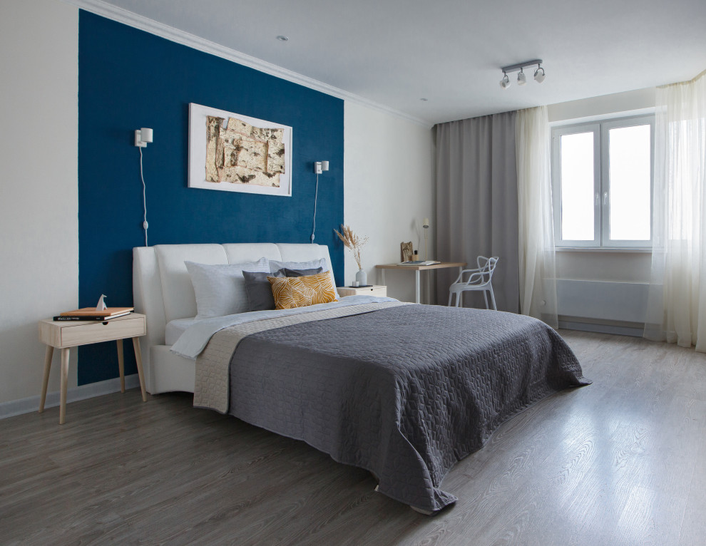 Modelo de dormitorio ecléctico pequeño con paredes azules, suelo laminado y suelo beige