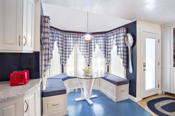 Example of a transitional l-shaped blue floor eat-in kitchen design in Boston with raised-panel cabinets, white cabinets, blue backsplash, white appliances, an island and white countertops