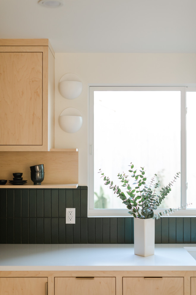 This is an example of a mid-sized scandinavian l-shaped open plan kitchen in Los Angeles with beige cabinets, green splashback, ceramic splashback, white appliances, concrete floors, with island, white floor and white benchtop.