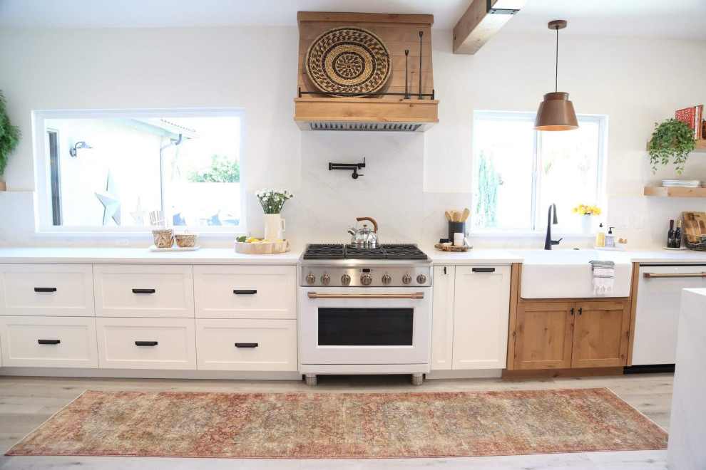 This is an example of a large modern single-wall eat-in kitchen in Other with a farmhouse sink, shaker cabinets, white cabinets, quartz benchtops, white splashback, engineered quartz splashback, white appliances, laminate floors, with island, grey floor, white benchtop and exposed beam.