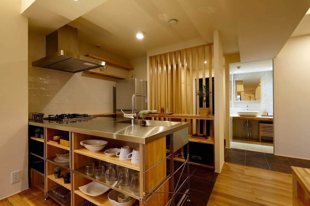 Photo of an asian kitchen in Other with an integrated sink, open cabinets, light wood cabinets, stainless steel benchtops, white splashback, stainless steel appliances and a peninsula.
