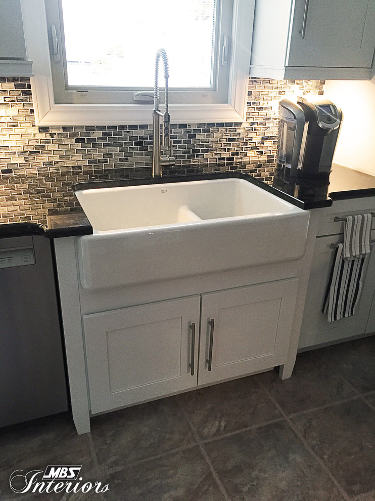 Example of a mid-sized transitional galley ceramic tile and beige floor eat-in kitchen design with a farmhouse sink, white cabinets, stainless steel appliances, shaker cabinets, granite countertops, blue backsplash, glass sheet backsplash and an island