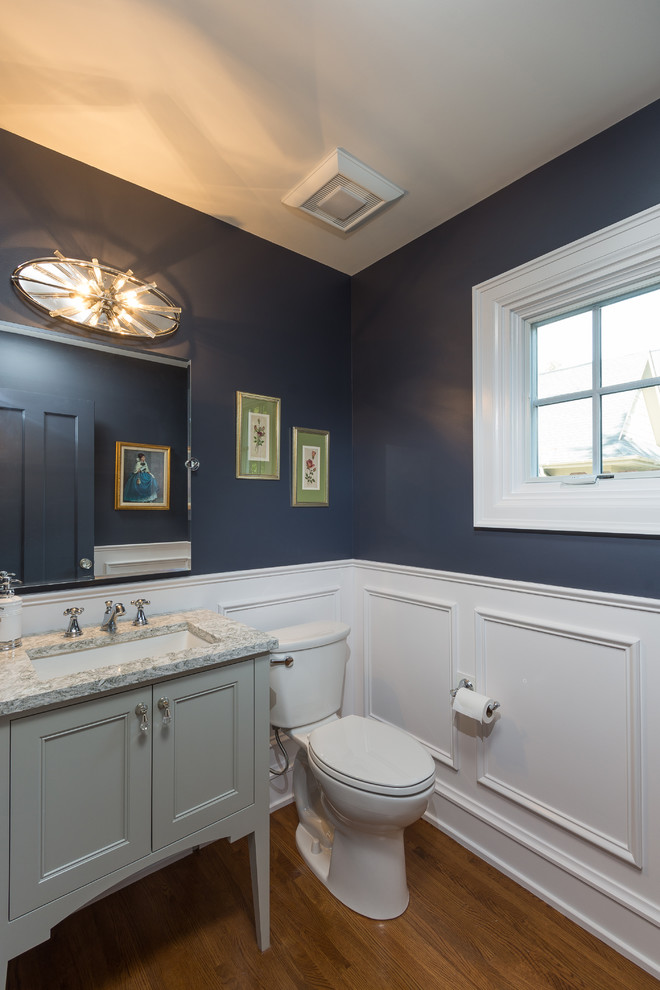 Photo of a mid-sized traditional powder room in Columbus with flat-panel cabinets, grey cabinets, a two-piece toilet, blue walls, medium hardwood floors, an undermount sink and engineered quartz benchtops.
