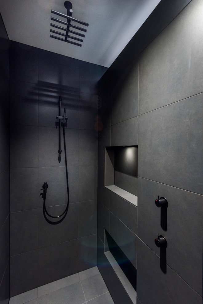 Mid-sized contemporary bathroom in Christchurch with light wood cabinets, a freestanding tub, an open shower, black tile, porcelain tile, porcelain floors, a wall-mount sink, solid surface benchtops, grey floor and an open shower.