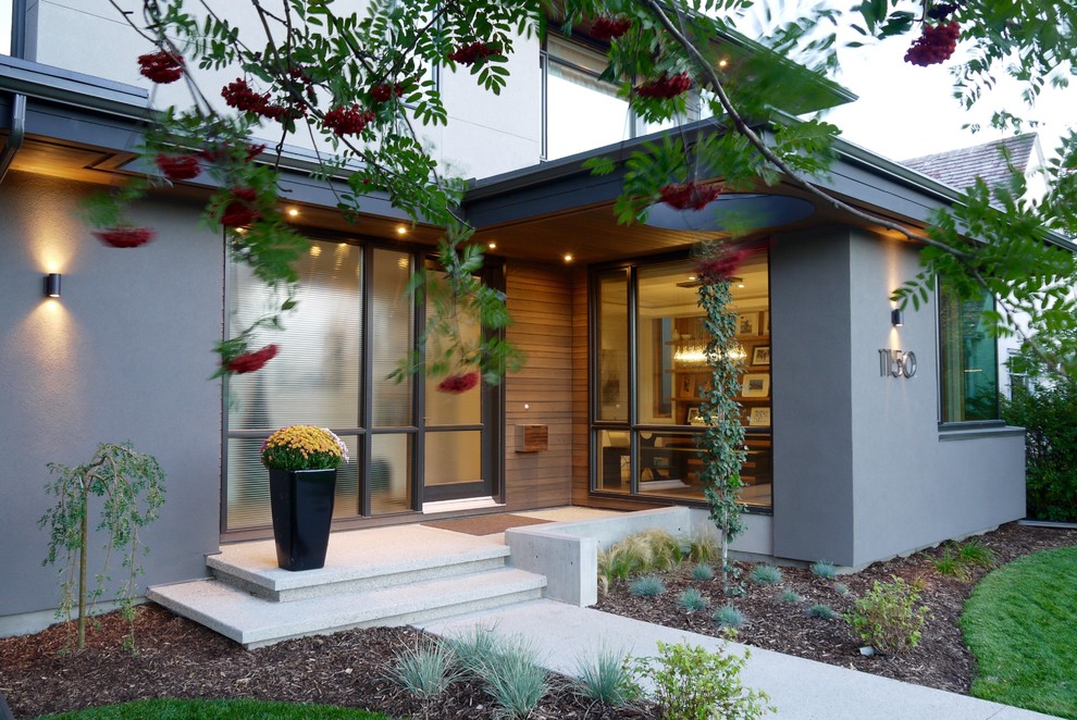 Design ideas for a large midcentury two-storey stucco brown exterior in Calgary with a hip roof.