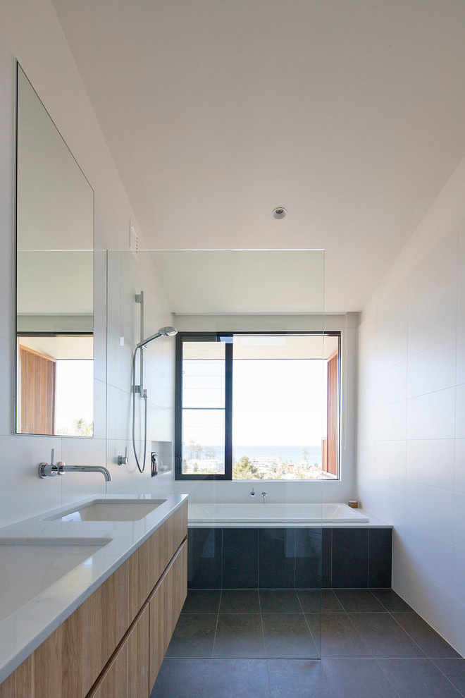 This is an example of a mid-sized contemporary master bathroom in Sydney with flat-panel cabinets, medium wood cabinets, an open shower, a one-piece toilet, white tile, ceramic tile, white walls, ceramic floors, an undermount sink, engineered quartz benchtops, beige floor and an open shower.