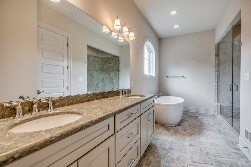 Freestanding bathtub - large transitional master beige tile and ceramic tile ceramic tile and brown floor freestanding bathtub idea with flat-panel cabinets, gray cabinets, a two-piece toilet, beige walls, an undermount sink, quartz countertops, a hinged shower door and beige countertops
