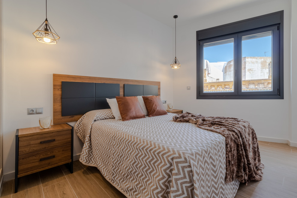 Ejemplo de dormitorio blanco y madera industrial pequeño con paredes blancas, suelo de baldosas de porcelana y suelo marrón