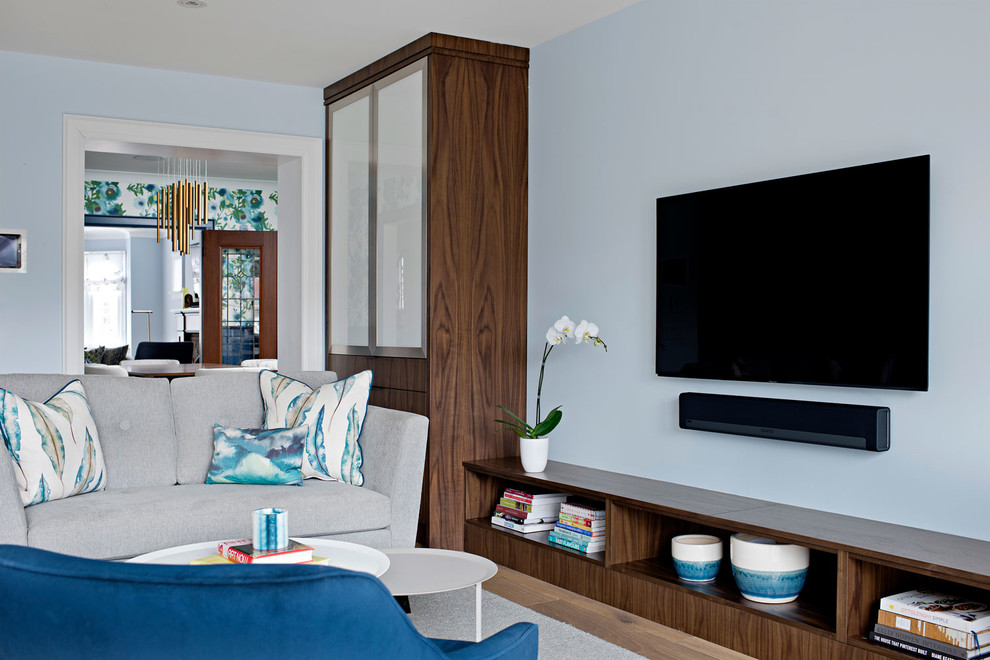 This is an example of a small modern open concept family room in Toronto with blue walls, light hardwood floors and a built-in media wall.