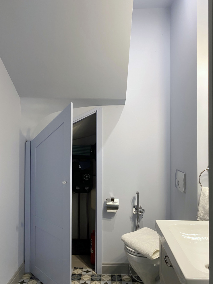 Inredning av ett klassiskt mellanstort toalett, med luckor med infälld panel, grå skåp, en vägghängd toalettstol, blå kakel, tunnelbanekakel, blå väggar, klinkergolv i porslin, ett nedsänkt handfat och flerfärgat golv