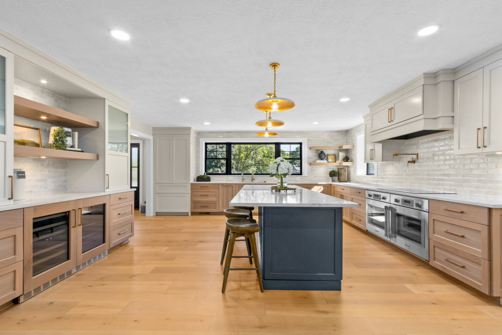 Example of a mid-sized transitional u-shaped open concept kitchen design with recessed-panel cabinets, white cabinets, quartzite countertops, stainless steel appliances and an island