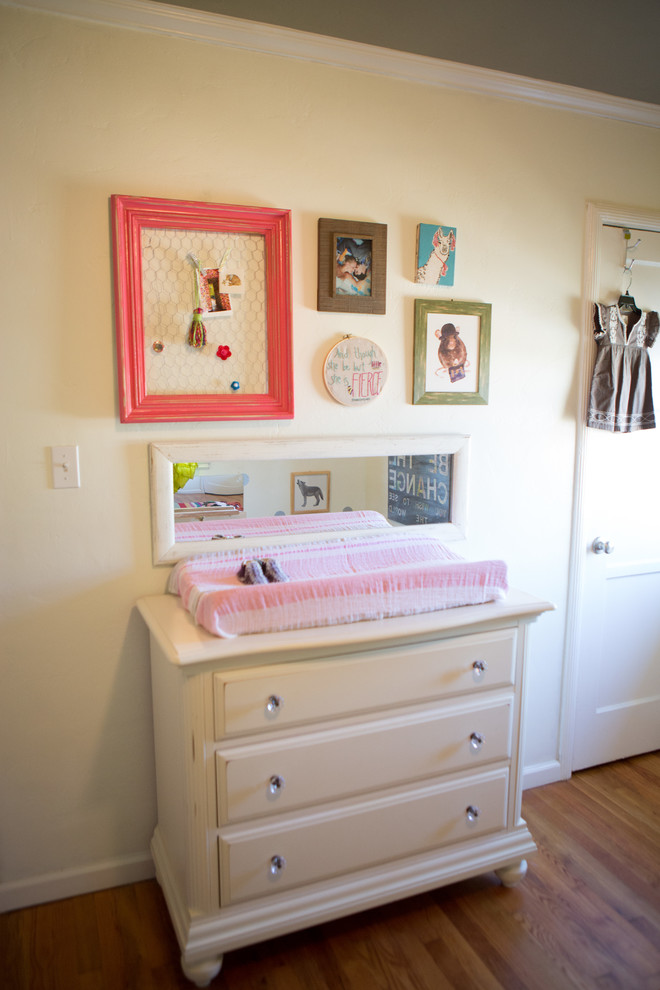 Inspiration for a mid-sized eclectic nursery for girls in San Diego with white walls and medium hardwood floors.