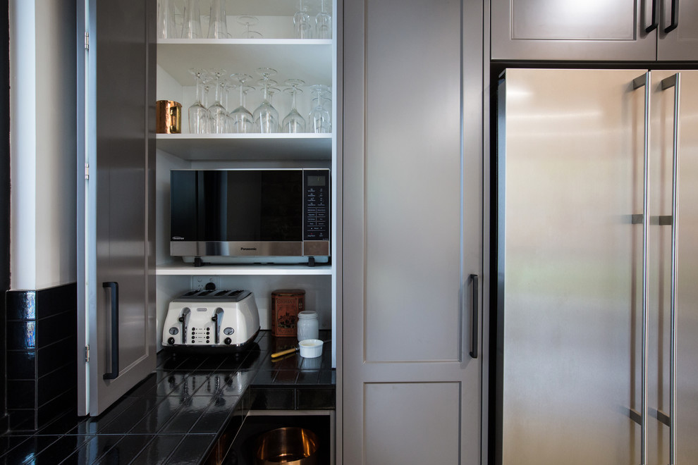 Design ideas for an expansive industrial galley kitchen pantry in Other with a double-bowl sink, shaker cabinets, grey cabinets, solid surface benchtops, black splashback, subway tile splashback, stainless steel appliances, concrete floors, with island, grey floor and white benchtop.