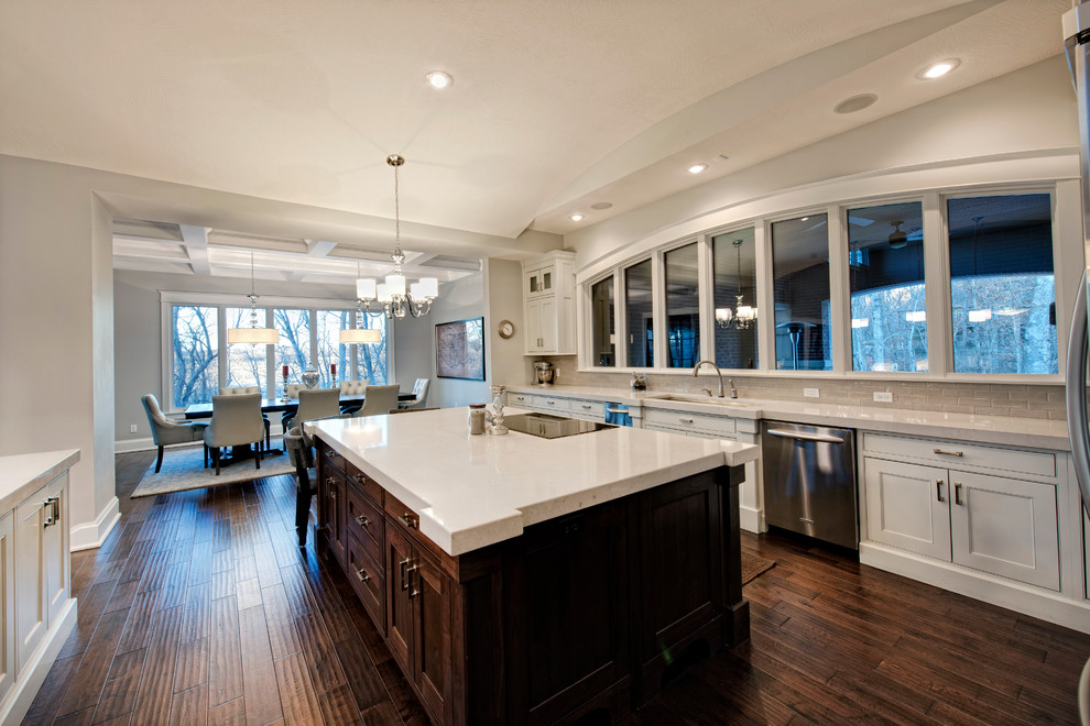 Inspiration for a mid-sized transitional u-shaped dark wood floor open concept kitchen remodel with beaded inset cabinets, quartz countertops, two islands, an undermount sink, white cabinets, beige backsplash, porcelain backsplash and stainless steel appliances