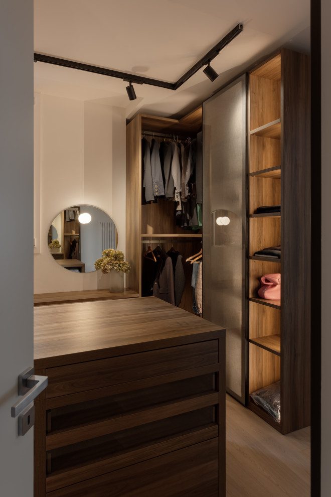 Пример оригинального дизайна: большая гардеробная комната унисекс в современном стиле с стеклянными фасадами, темными деревянными фасадами, деревянным полом и бежевым полом