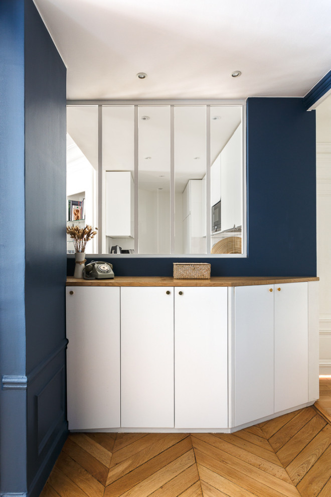 Imagen de distribuidor de tamaño medio con paredes azules, suelo de madera clara, puerta simple, puerta azul y suelo beige