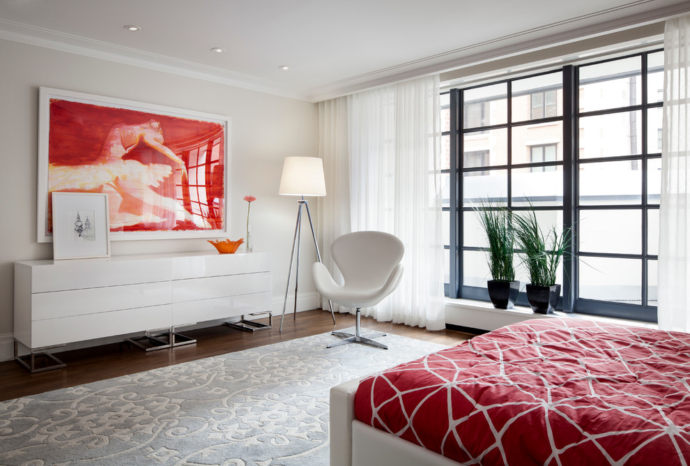 This is an example of a contemporary bedroom in New York with beige walls and dark hardwood floors.