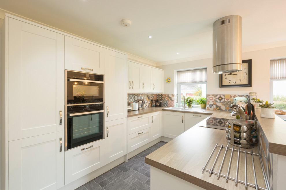 Mid-sized contemporary u-shaped eat-in kitchen in Other with a double-bowl sink, shaker cabinets, white cabinets, wood benchtops, multi-coloured splashback, ceramic splashback, stainless steel appliances, ceramic floors, grey floor and brown benchtop.