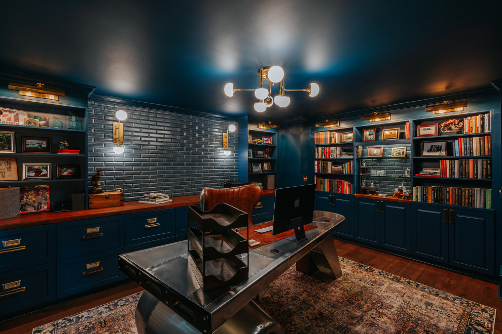 Eklektisk inredning av ett mellanstort hemmabibliotek, med blå väggar, mellanmörkt trägolv, ett fristående skrivbord och brunt golv