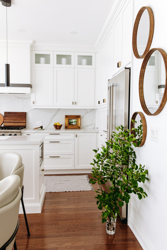 Example of a mid-sized transitional l-shaped dark wood floor and brown floor eat-in kitchen design in Toronto with an undermount sink, shaker cabinets, white cabinets, quartz countertops, white backsplash, quartz backsplash, black appliances, an island and white countertops