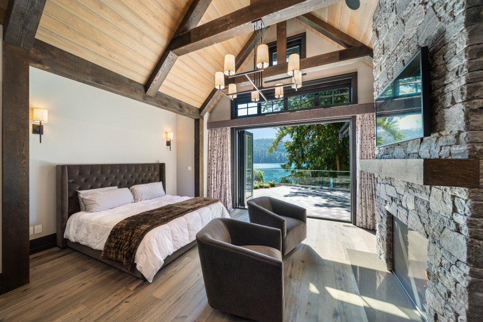 Mid-sized country master bedroom in Vancouver with grey walls, medium hardwood floors, a standard fireplace, a stone fireplace surround, grey floor and vaulted.
