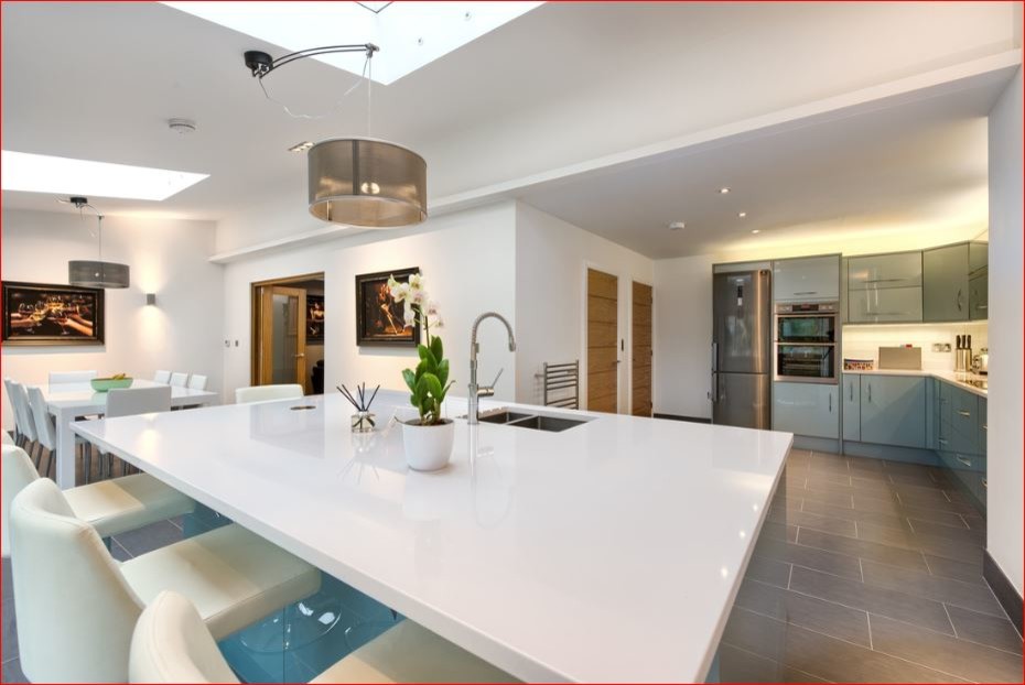 Design ideas for a mid-sized contemporary l-shaped open plan kitchen in Cambridgeshire with a drop-in sink, flat-panel cabinets, blue cabinets, white splashback, matchstick tile splashback, stainless steel appliances, ceramic floors and with island.