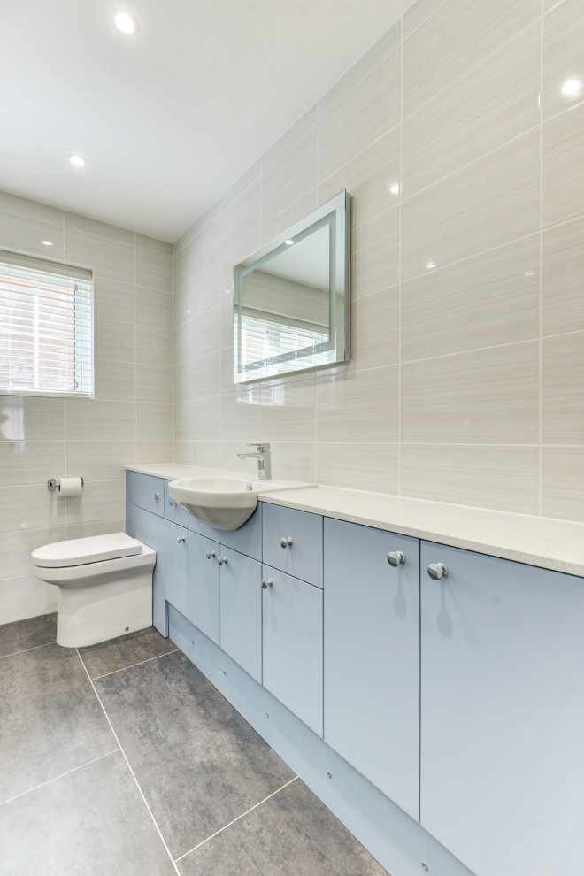 Medium sized contemporary grey and white family bathroom in Sussex with flat-panel cabinets, blue cabinets, an alcove bath, a shower/bath combination, a wall mounted toilet, beige tiles, ceramic tiles, beige walls, an integrated sink, laminate worktops, grey floors, white worktops, feature lighting, a single sink and a built in vanity unit.